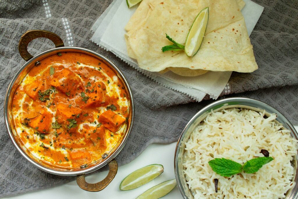 Butter chicken in a copper bowl with basmati rice and naan