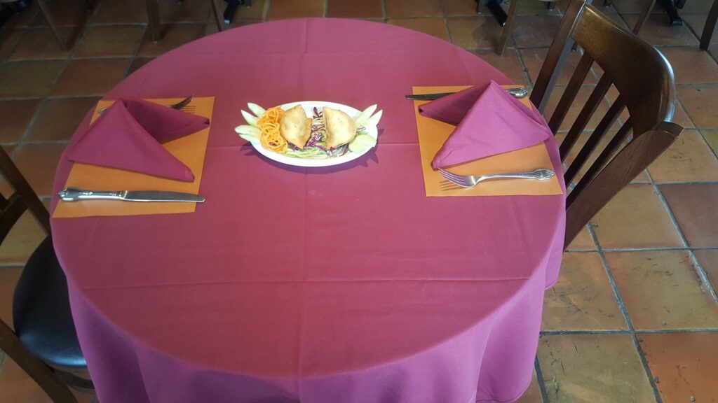 A plated dish on a table set for two